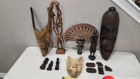 Various African wooden carvings and masks arranged on a table for an overview of the lot.