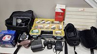 Photo showing untested lot with cameras, bags, lens, organized plastic case with labeled compartments for filters, cleaning supplies and accessories.