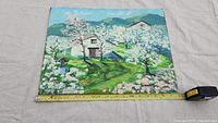 Full front view of oil painting on canvas panel laid flat, showing spring orchard scene with measuring tape for size reference