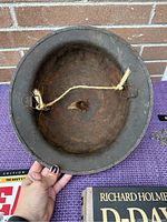 Rusty WWI style helmet shown from underside with inner strap tied with string.