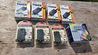 Multiple Woods timers, four in boxes and three in plastic blister packs, plus one box of NOMA Christmas lights.