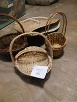 Four wicker baskets displayed together on the floor in various shapes and sizes.