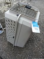 Side view showing beige plastic body with ventilation slots and top metal door with latch.