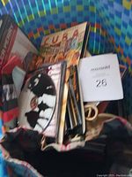 Photo showing various CDs and DVDs inside a fabric-lined basket, including visible titles and covers like Tyler Perry and Cuba theme.