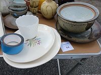 Antique ceramic bowl sitting on a ceramic plate with white scalloped pot and floral decorative plate underneath.