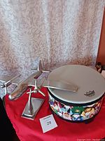 Kids drum with colorful cowboy themed sides and white Remo drum head next to metal airplane decoration on red cloth