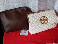 Photo shows two handbags side by side, a brown leather one and a white quilted one with a gold-tone logo.