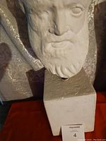 Close-up image of the white sculpted bust showing detailed facial features and pedestal base