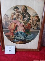 Framed circular antique religious wall art on cloth material within a wooden frame, showing the full piece.