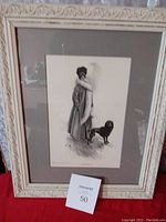 Framed black and white print showing Helen Keller standing on a street with a dog, framed in an ornate light wood frame