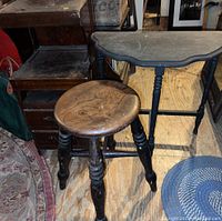 Photo showing the wooden round stool with turned legs in front of the half moon table and wooden telephone table on a wood floor with rug.