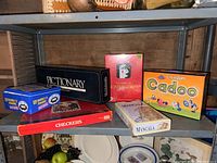 Shelf with six assorted games: Pictionary, Categories, Cadoo, Double 15 Dominoes, Checkers, and Mancala.
