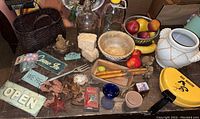 Overview of wooden bowls, signs, baskets, artificial fruit, and other vintage decor items spread on a wooden surface.