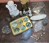 Entire collection of assorted vintage items including ceramic vase, brass pitcher, brass tray, glass containers, salt and pepper shakers, glass dishes, metal tray, and demi spoons.
