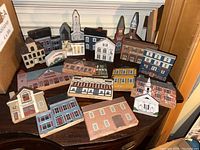 View of 21 assorted Cats Meow miniature buildings arranged closely, showing a variety of church, school, and house designs with painted details.