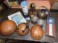 Photo showing carved wooden bowls, copper kettle, wood signs, decorative candle holder, flower pot, and spherical carvings.