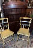 Full view of the solid wood vintage cupboard with two painted antique chairs placed in front