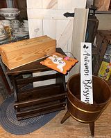 Wooden door, small table, wooden stand, autumn and Halloween themed signs, and a wooden planter bucket all visible.