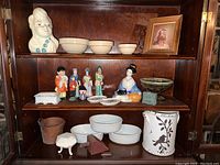 Full view of wooden shelf displaying the vintage ladies head vase, assorted figurines, various ceramic bowls, and decorative items.