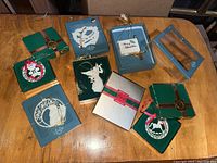 Top view of seven Lenox ornaments in original boxes arranged on a wooden surface, showing a mix of green and blue boxes and some with red ribbons.