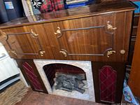 Mid century electric fireplace bar combo showing pull down front panels and textured wood with brass accents.