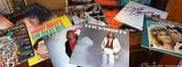 Vintage vinyl records spread out on a table showing cover art and titles including disco dancing themed album and other vintage records.