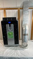 Front view of commercial portable air conditioner with exhaust tube and window insert, showing overall condition and accessory items.