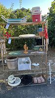 Full view of metal rack with various garden items including cooler, planter trays, pots, garden decor and tools