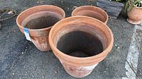 Three large terra-cotta pots grouped together outside. Pots show weathering and surface staining.