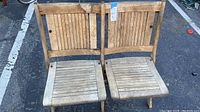 Front view of the vintage two-seater teak folding chair showing both seats and backrests with weathered wood.