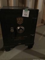 Front view showing combination dial, locking handle, caster wheels, auction tag ‘104’