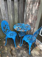 three-piece blue metal bistro set with round table and two chairs on outdoor deck