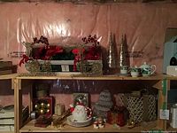 Shelf display with red poinsettias, gold wire reindeer, gold cone trees, and Christmas tea set