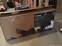 Photo showing the box of a NOMA 6.5 foot Lighted Brentwood Pine Christmas Tree with 450 tips