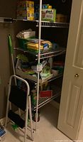 Photo of shelving with assorted cleaning and kitchen supplies including boxes of bags and rolls.