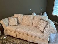 Front view of cream brocade 3-seater sofa with 2 matching throw pillows on either end