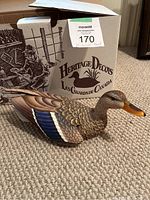 Wooden Hen Mallard duck decoy with original box behind it showing Heritage Decoys branding and auction lot sticker.
