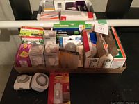 Photo showing multiple light bulb boxes, timers, and packaging inside basket on white tray