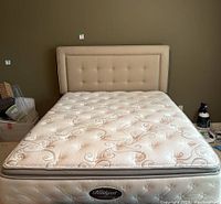 Full assembled queen bed with mattress, box spring and headboard against wall