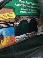 Close-up photo of product packaging showing NuVue Winter Plant/Shrub Cover branding, explaining synthetic weave technology and winter protection benefits.