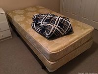 Overall view of metal bed frame with mattress, box spring and folded bedspread