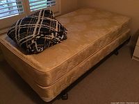 Full view of twin mattress and box spring set on metal frame with casters