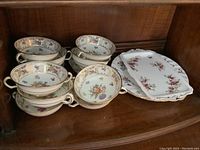 Eleven floral patterned bone china bouillon bowls, stacked showing gold trim and floral designs