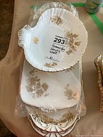 Stack of four Hammersley fine bone china serving pieces showing gold floral designs and gilded edges, including shell-shaped dishes and trays.