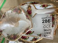 Porcelain cake cutter and small server plate with Old Country Roses floral pattern and gold trim seen with lot label.