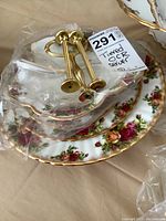 Three stacked plates of the three-tier OCR server with gold handles wrapped, showing floral rose pattern with gold trim.