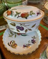 Photo of roaster with lid showing fruit and leaf pattern and scalloped pie plate underneath.