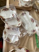 Five Royal Albert Old Country Roses small serving ware pieces wrapped in plastic and displayed on a table.