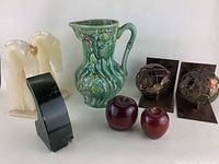 Overall display of lot with all items: onyx horse head bookends, green ceramic pitcher, metal sphere bookends, wedge-shaped stone bookend, and wooden apples.