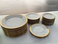 Three stacks of plates: large dinner plates, medium salad plates, small bread plates